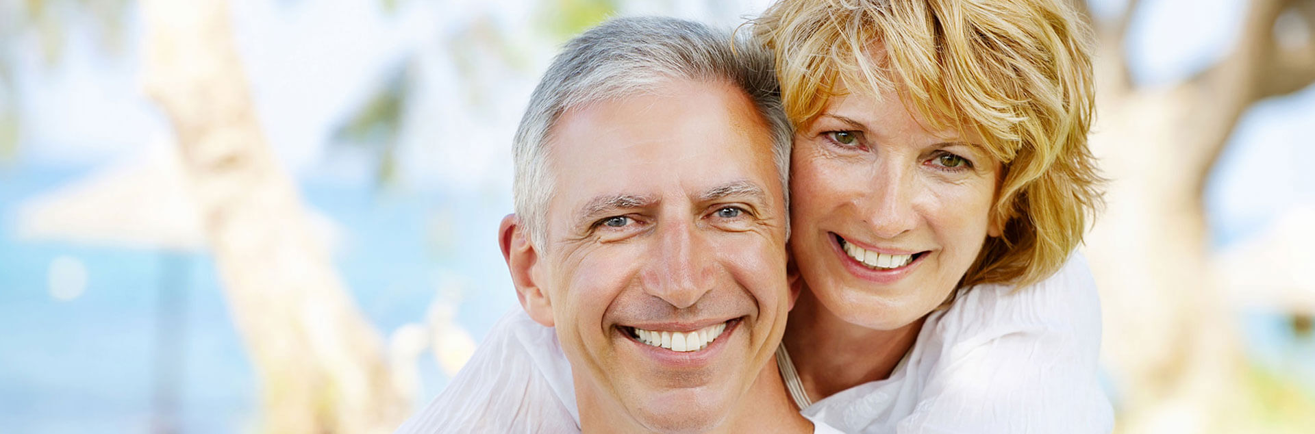 Elderly couple embracing each other and smiling after using dentures and partials