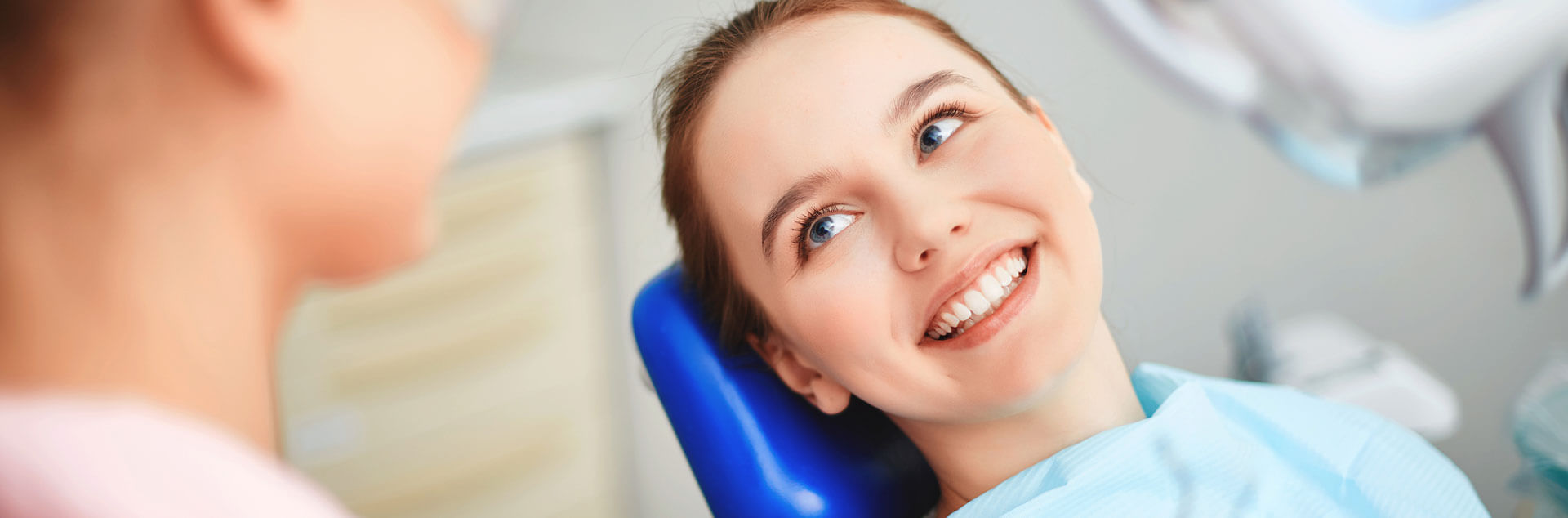 Young beautiful woman smiling seated at dental chair for Nobel Implants